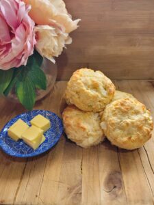 four cheese and onion scones sitting on a wooden board with butter on the side