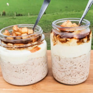 to jars of overnight oats sitting on a fence post