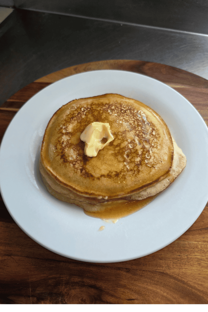 fluffy pancakes on a white plate with butter and lemon juice dripping over it