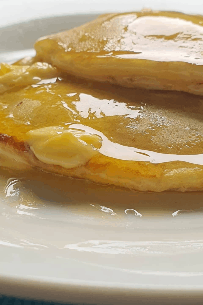 fluffy pancakes on a white plate with butter and lemon juice dripping over it