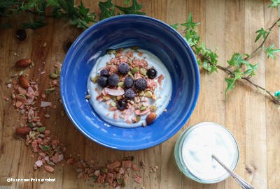 blue bowl on a wooden board with dairy free coconut yogurt, muesli and blueberries