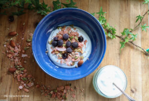 a bowl of coconut yogurt sitting on a wooden board