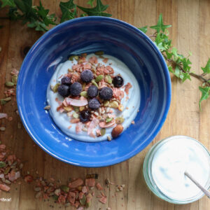 a bowl of coconut yogurt sitting on a wooden board