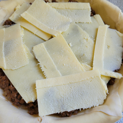cheese slices on top of beef mince in a pie