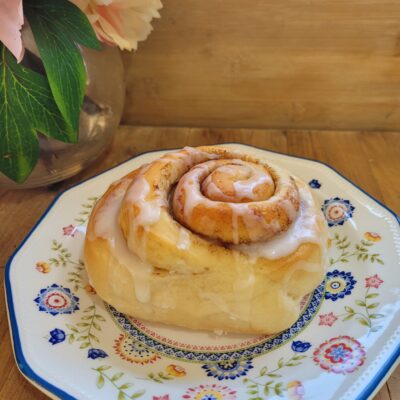 The Easiest Cinnamon Scrolls sitting on a china plate topped with white icing