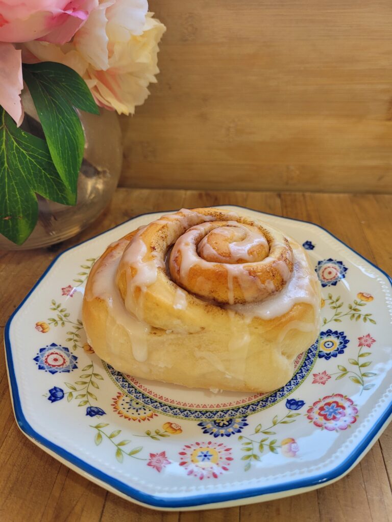 The Easiest Cinnamon Scrolls sitting on a china plate topped with white icing