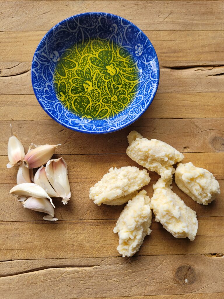 frozen pucks of garlic with sunflower oil and garlic cloves on a wooden board