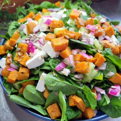 roasted sweet potato, spinach,red onion and feta salad in a blue bowl