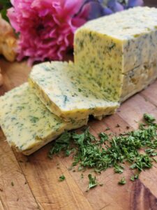 a block of butter with garlic and herbs in it cut into squares on a wooden board