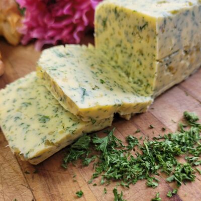 a block of butter with garlic and herbs in it cut into squares on a wooden board