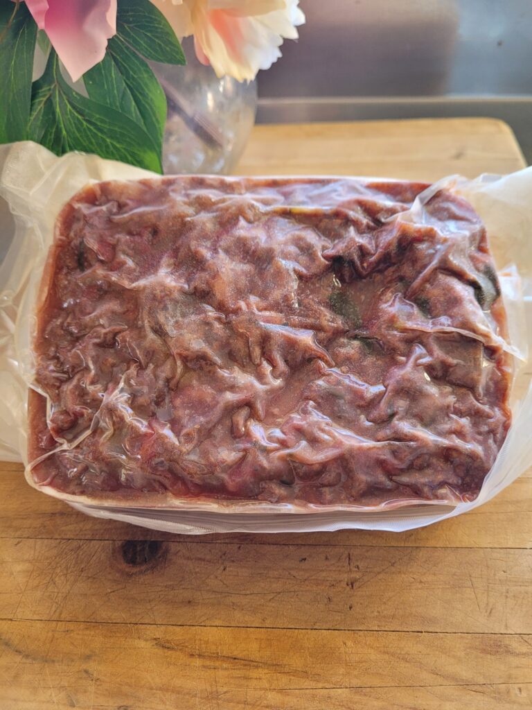 A packet of frozen red meat sauce on a wooden board