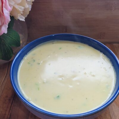 A steamy bowl of creamy chicken soup on a wooden board