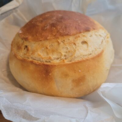 A round loaf of no-knead bread on baking paper just out of the oven