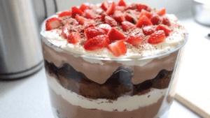 Chocolate cherry trifle in a glass bowl with strawberries on top