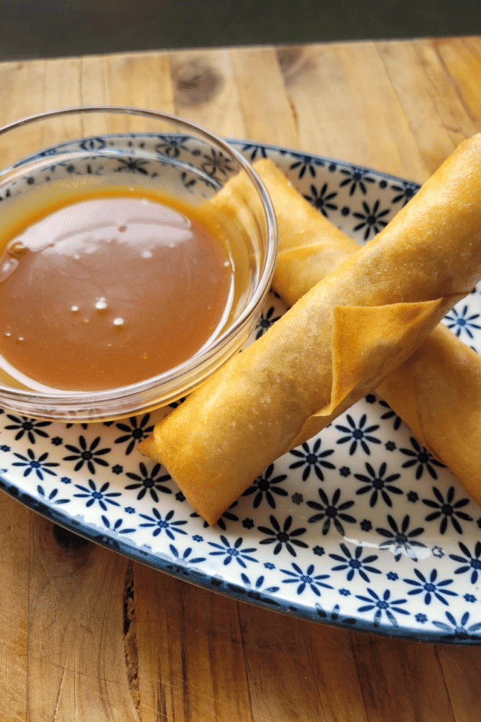 salted caramel sauce with apple pie spring rolls on a lovely blue and white plate on a wooden board