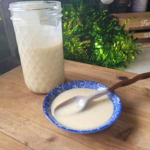 Sweetened Condensed Milk Salad Dressing in a glass jar and in a small bowl with a wooden teaspoon