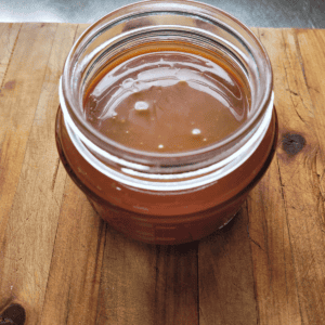 a jar of homemade salted caramel sitting on a wooden board