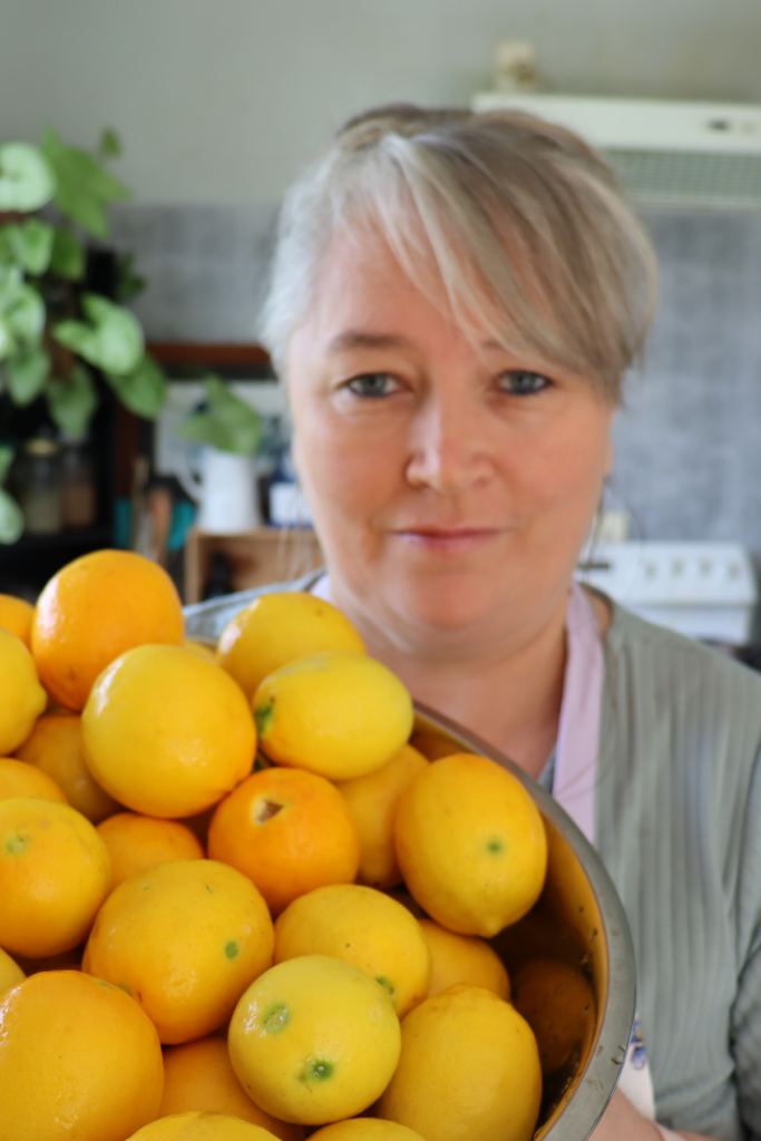 lady holding a huge bowl of yellow lemons in her kitchen