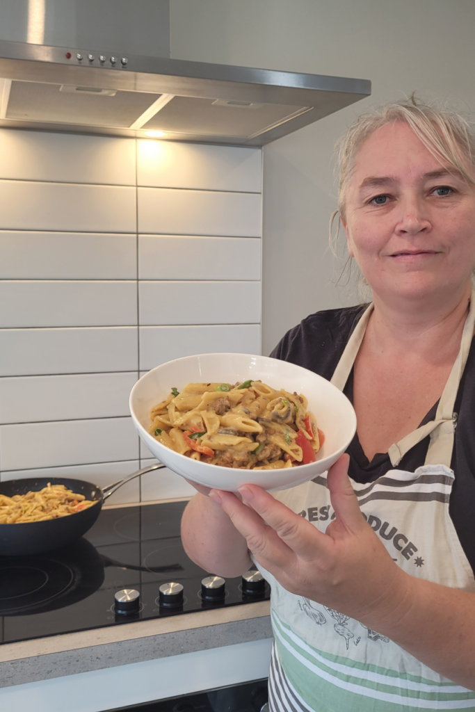 farmers wife homestead standing holding a bowl of creamy pork pasta