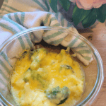 Easy Freezer Broccoli & Cauliflower Cheese Sauce in a bowl sitting on a wooden board it is topped with melted gooey cheese