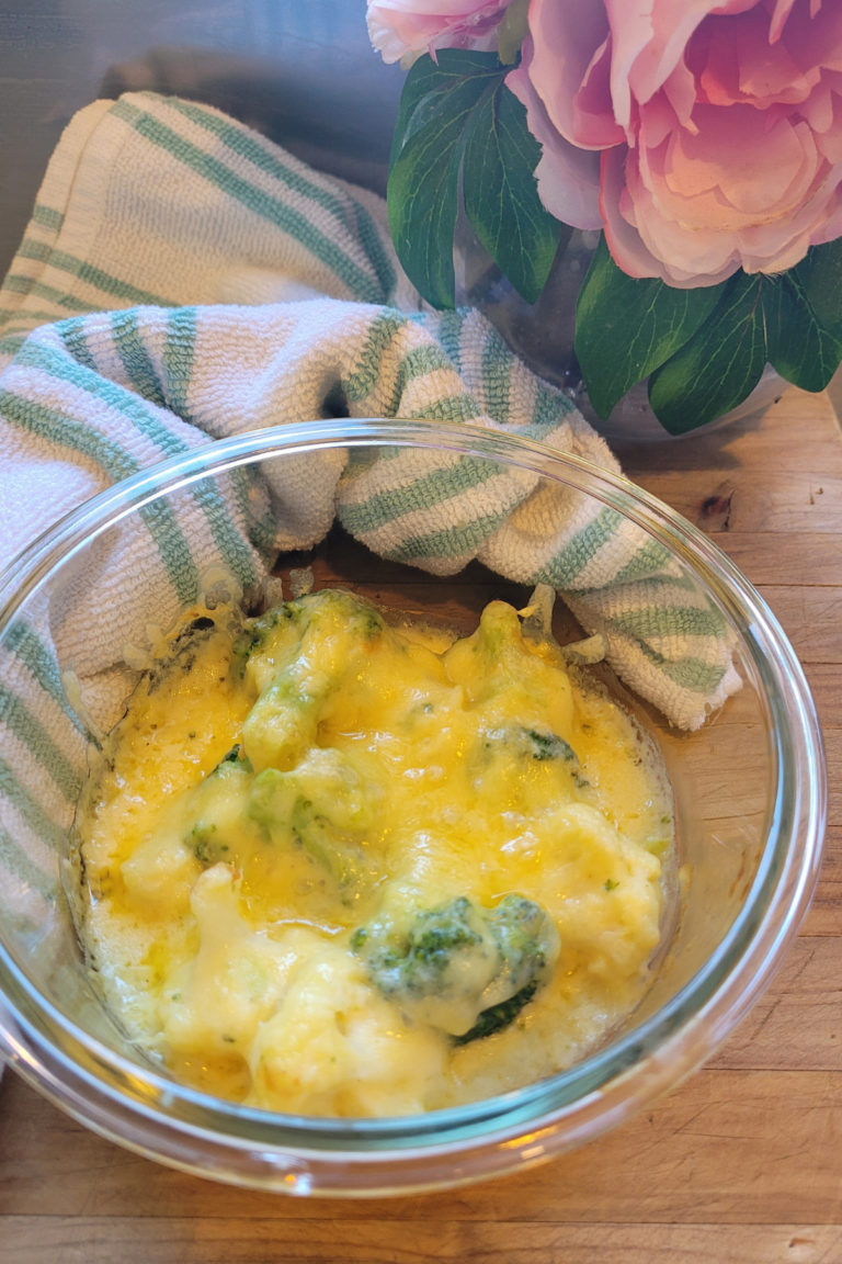 Easy Freezer Broccoli & Cauliflower Cheese Sauce in a bowl sitting on a wooden board it is topped with melted gooey cheese