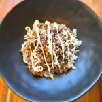 chicken teriyaki on rice with kewpie mayo over the top in a black bowl