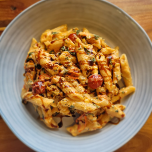 viral tomato pasta with cream cheese and cherry tomatoes in a grey bowl on a wooden bench