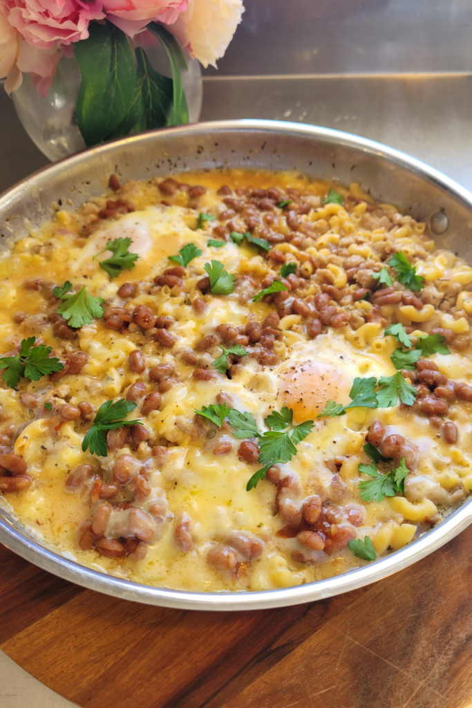 breakfast mac and cheese in a frying pan with soft poached eggs on the top