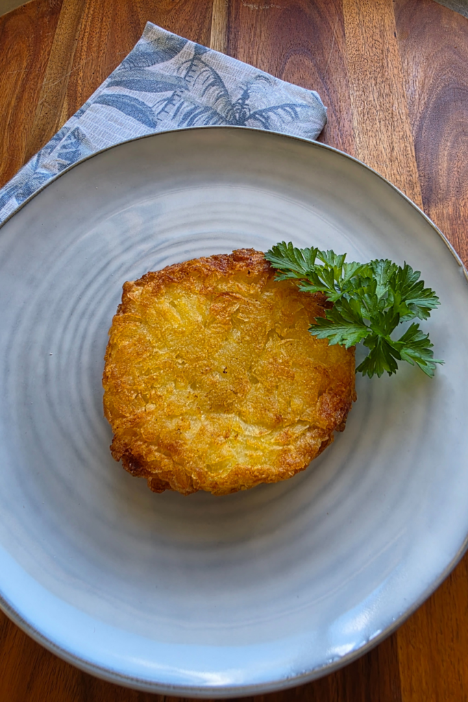 crispy hash brown on a blue plate sitting on a wooden board