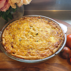 tomato pie topped with gooey cheese on a wooden board