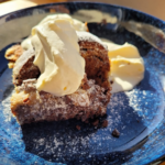hot cross buns bread and butter pudding on a blue plate with whipped cream