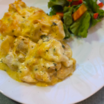 creamy and cheesy chicken alfredo tortellini bake on a white plate with a side salad