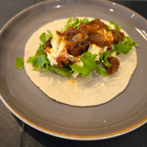 Slow-cooked chipotle beef served on a soft taco with lettuce, diced tomato, cheese and topped with sour cream