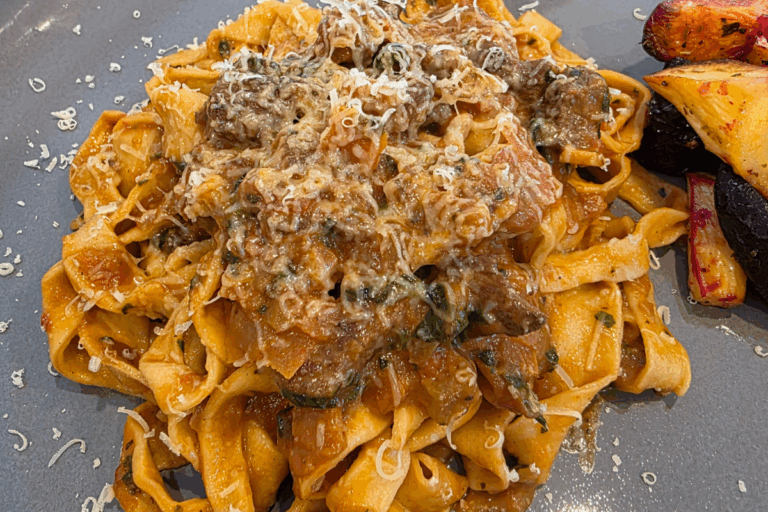 a dish or homemade pasta with a slow-cooked lamb ragu with shaved cheese over the top