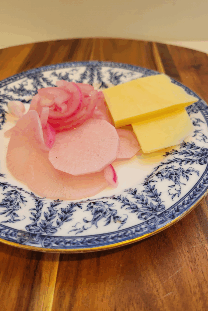radish and red onion pickle on a blue and white plate with some slices of mild cheese