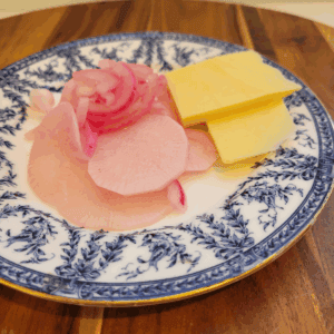 red onion and radish pickle on a blue plate. It has two slices of cheese as well.
