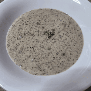 a bowl of creamy mushroom soup in a white bowl