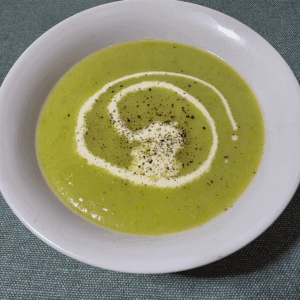 leek and potato soup in a white bowl, with a swirl of cream