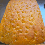 Close-up of golden homemade focaccia bread with fresh rosemary on top