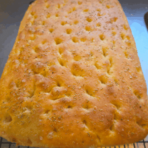 Close-up of golden homemade focaccia bread with fresh rosemary on top