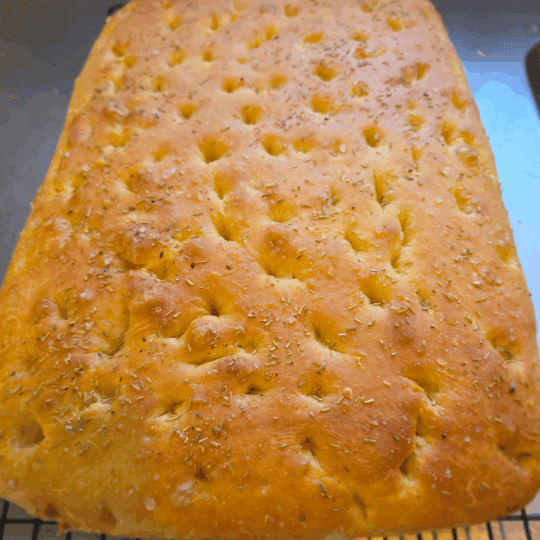 Close-up of golden homemade focaccia bread with fresh rosemary on top