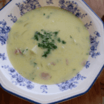 a bowl of hearty potato, bacon, and onion soup in a blue china bowl