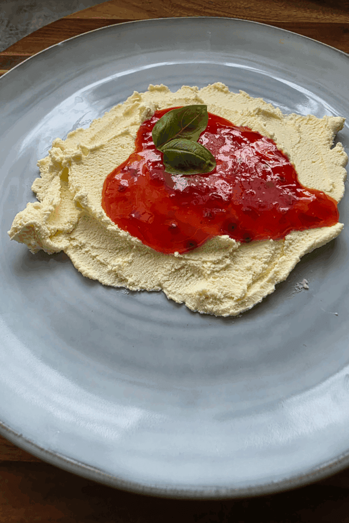 A blue plate with some home made cream cheese spread out. Topped with sweet chilli sauce