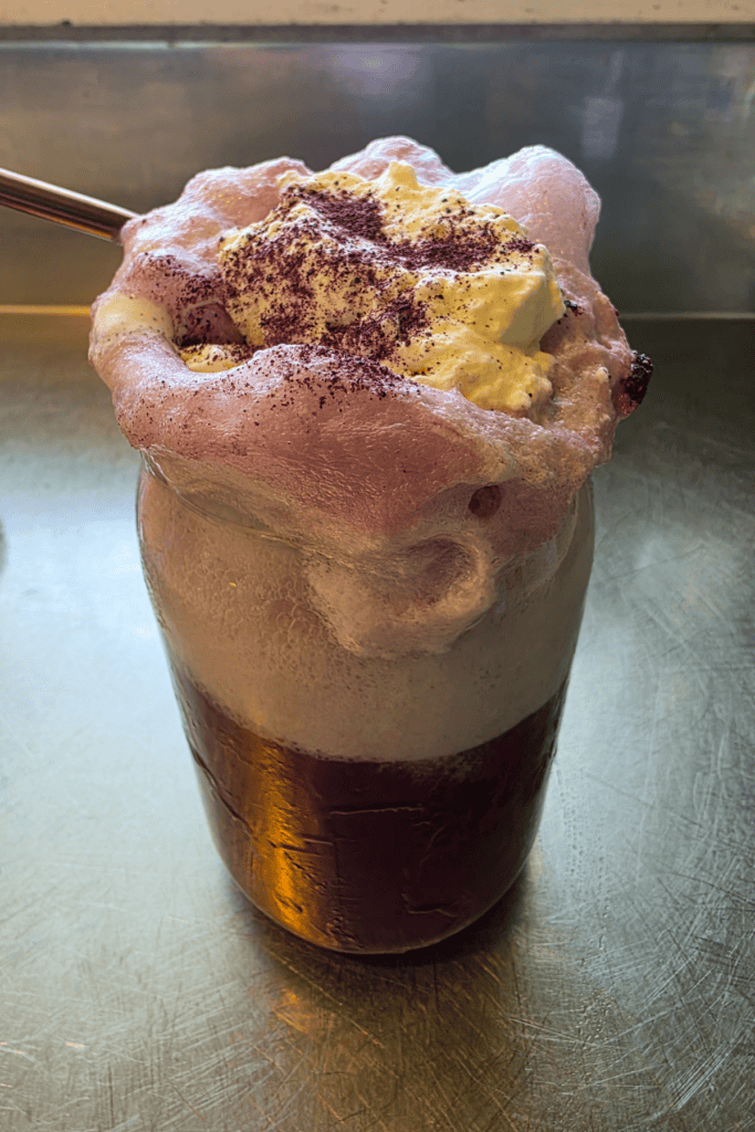 glass of blueberry float with ice cream and topped with whipped cream