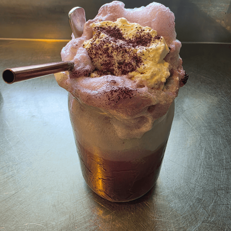 a glass of blueberry floats topped with whipped cream and overflowing the jar