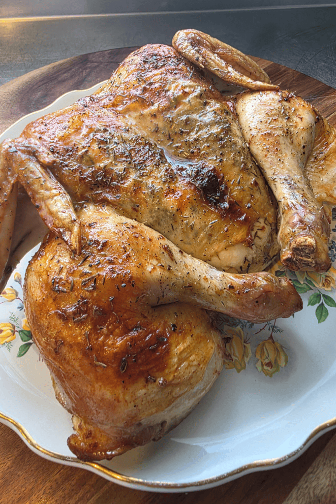 “Butterflied lemon and thyme chicken roasted golden brown on a tray.”