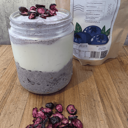 blueberry over night oats in a glass jar with yoghurt and freeze dried blueberries