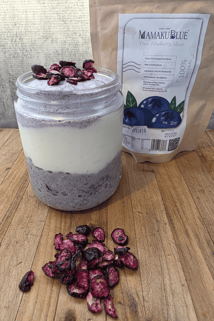 blueberry over night oats in a glass jar with yoghurt and freeze dried blueberries