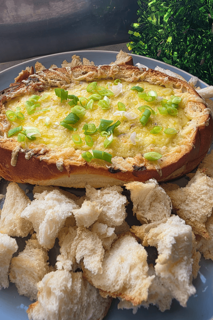 cobb loaf on a blue platter with bread pieces surrounding it. A warm dip.