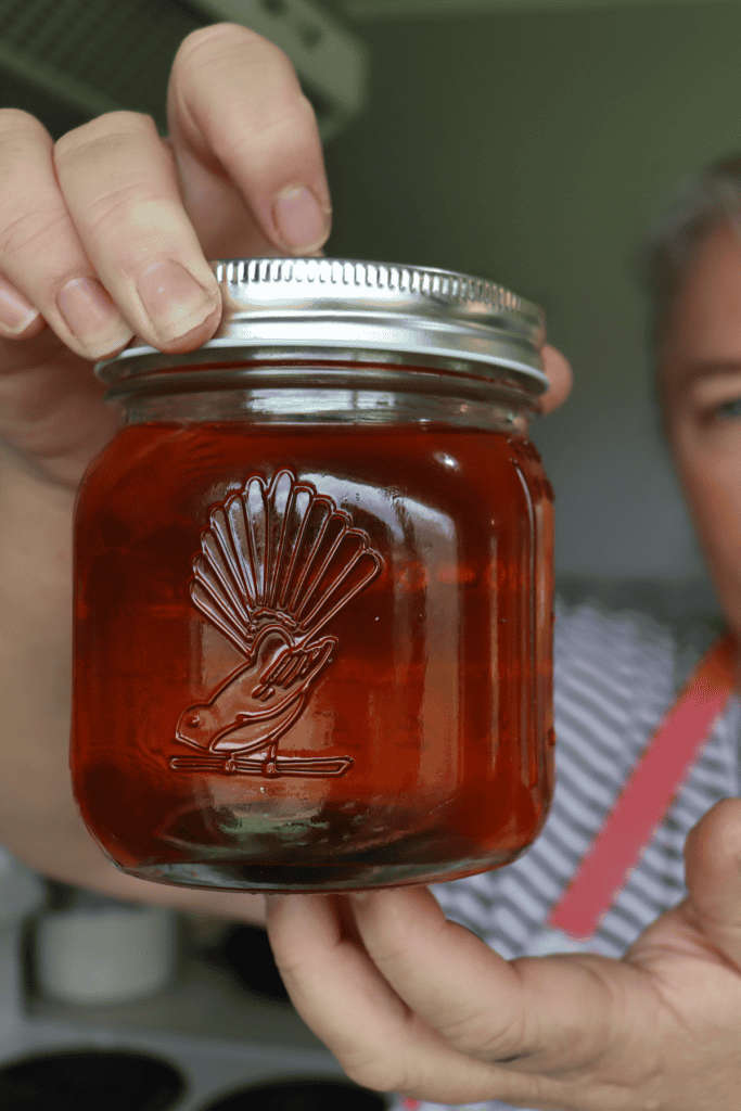 A jar of easy homemade golden syrup being held.